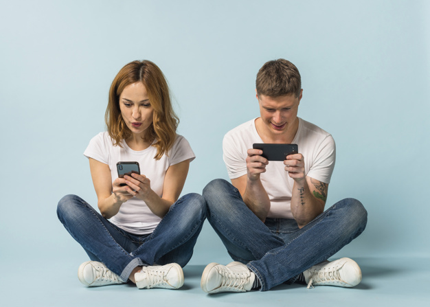 dois jovens usando o celular em fundo azul