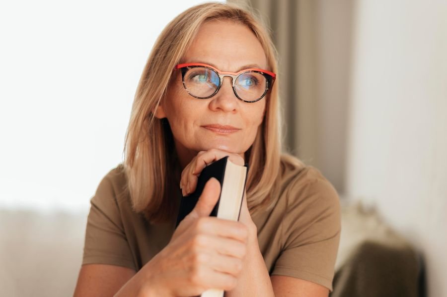 Mulher de óculos apoiada em livro